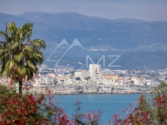 Vue panoramique sur la mer depuis une villa à Cap d'Antibes, avec des montagnes en arrière-plan.