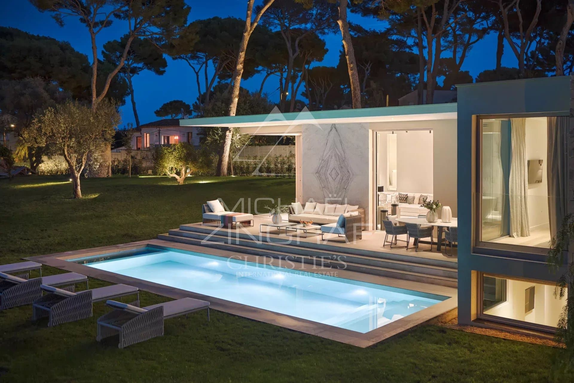 Villa moderne avec piscine et jardin à Antibes, vue sur la mer au crépuscule.