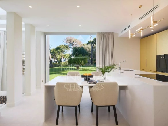 Intérieur moderne d'une villa de luxe avec cuisine ouverte et vue sur le jardin.