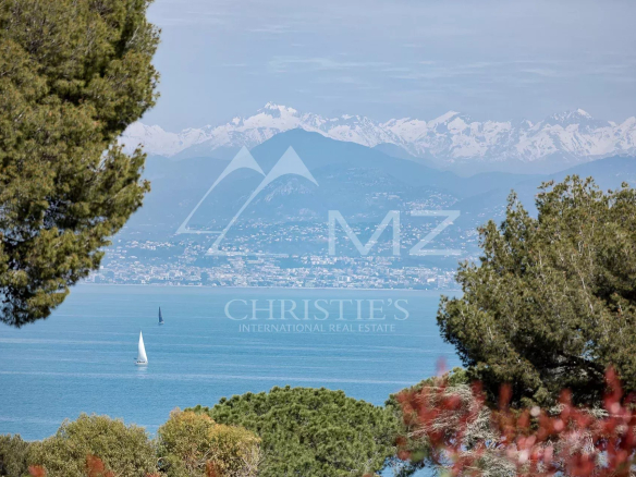 Vue panoramique sur la mer depuis une villa à Antibes, avec des montagnes en arrière-plan.