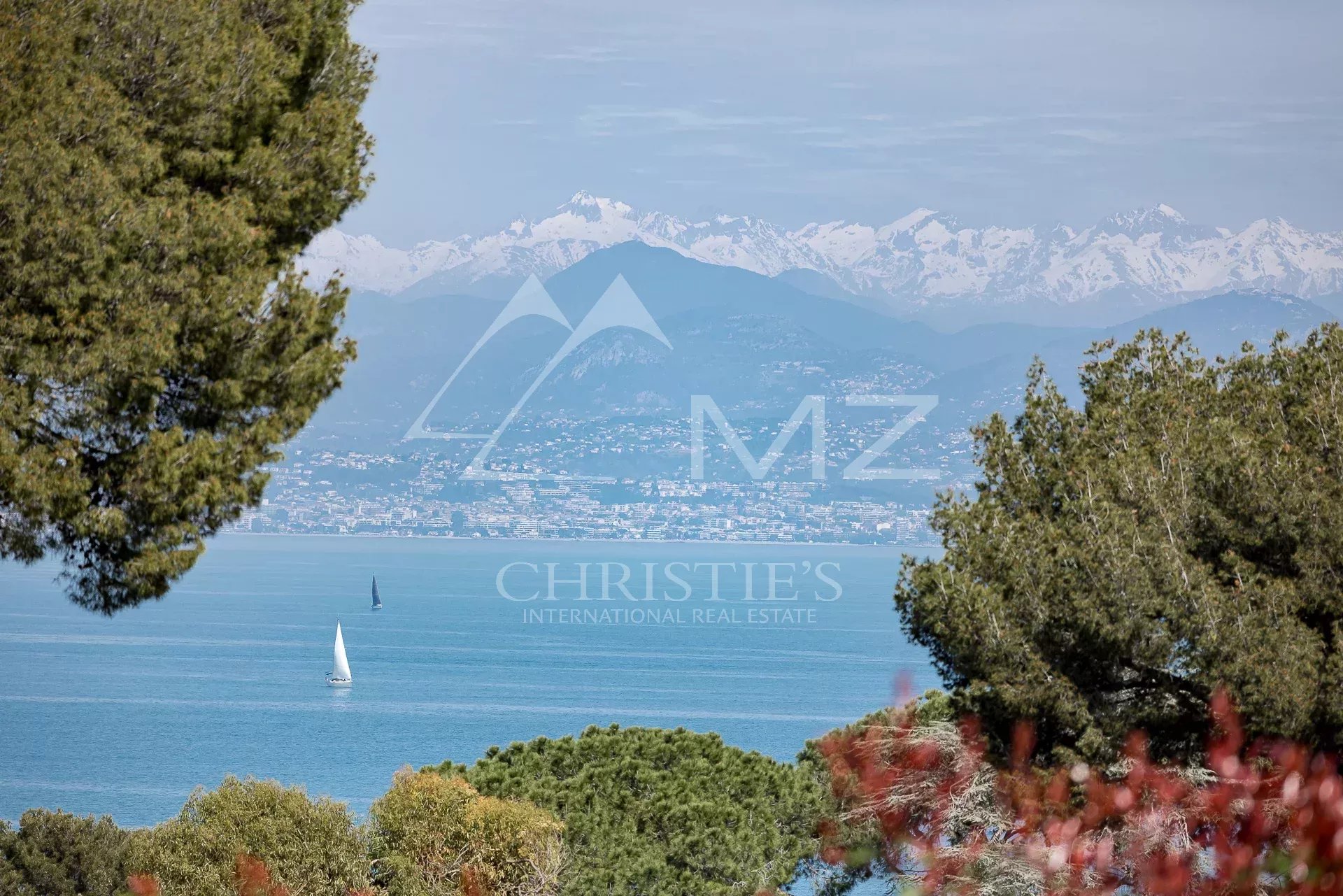 Vue panoramique sur la mer depuis une villa à Antibes, avec des montagnes en arrière-plan.