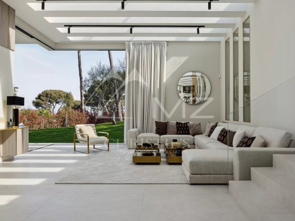 Intérieur d'une villa moderne avec salon lumineux et vue sur le jardin à Antibes.