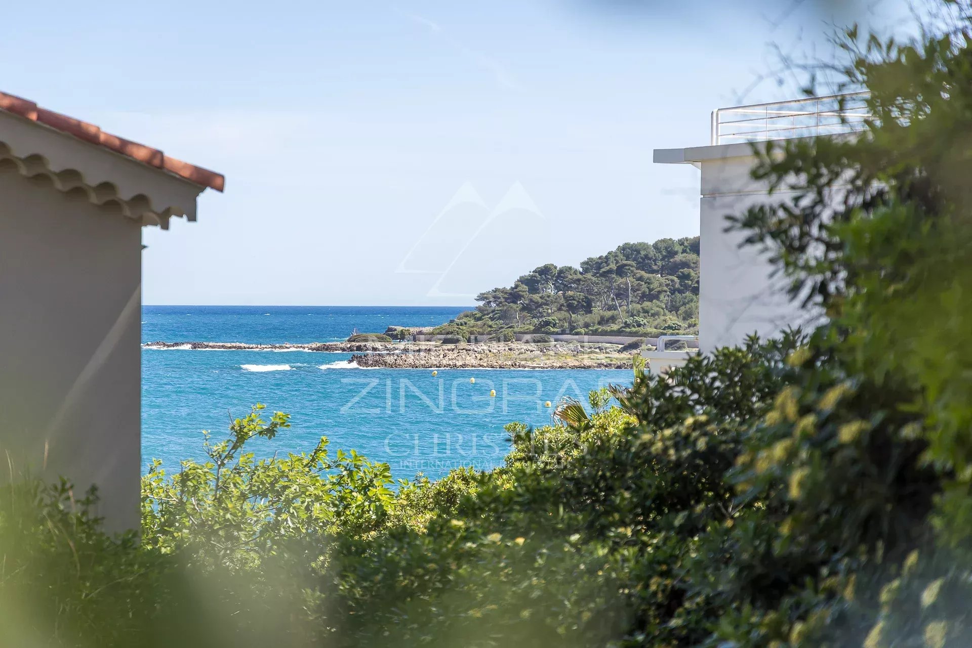 Vue mer depuis une villa à Cap d’Antibes Vue de la mer depuis une villa rénovée à Cap d'Antibes, entourée de verdure.