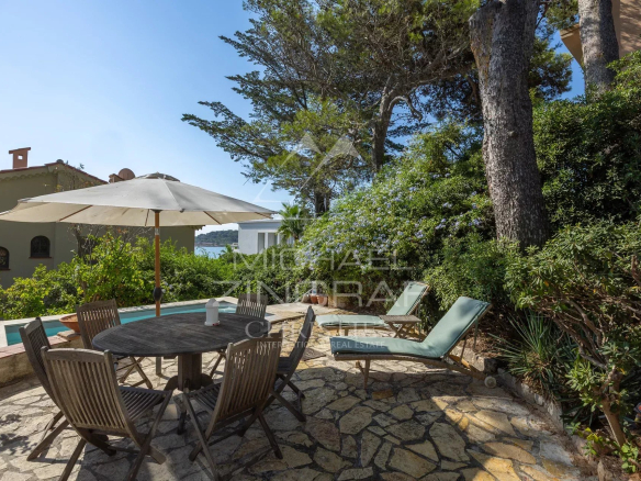 Terrasse d'une villa rénovée avec vue mer à Cap d’Antibes, mobilier de jardin et parasol.