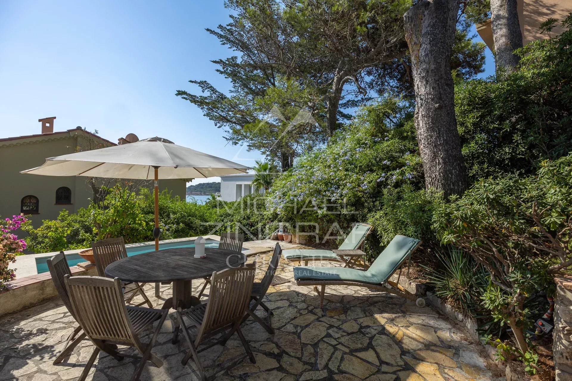 Terrasse de villa à Cap d’Antibes Terrasse d'une villa rénovée avec vue mer à Cap d’Antibes, mobilier de jardin et parasol.