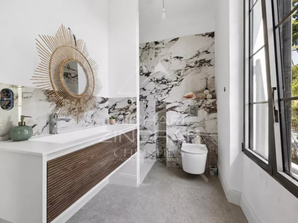 Salle de bain moderne avec miroir rond et décor en marbre.