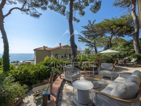 Terrasse d'une villa rénovée avec vue sur la mer à Cap d'Antibes, entourée de verdure.