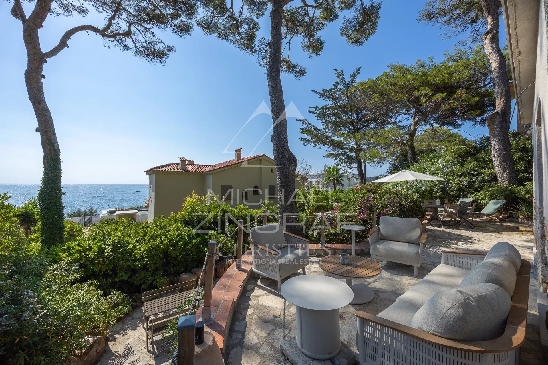 Villa rénovée avec vue mer à Cap d’Antibes Terrasse d'une villa rénovée avec vue sur la mer à Cap d'Antibes, entourée de verdure.