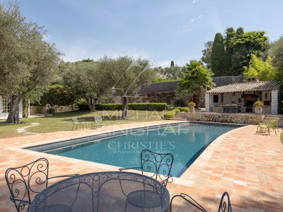 Provençal farmhouse with swimming pool and garden in Cap d'Antibes, surrounded by olive and palm trees.