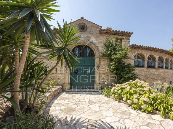 Stone property with garden in Cap d'Antibes, surrounded by plants and a stone walkway.