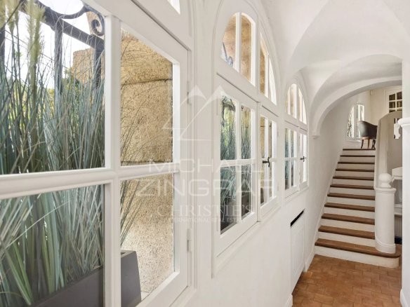 Interior of a Provençal farmhouse with arched windows and a wooden staircase in Antibes.