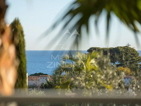 Vue sur la mer depuis un appartement au Cap d'Antibes, avec des palmiers en avant-plan.