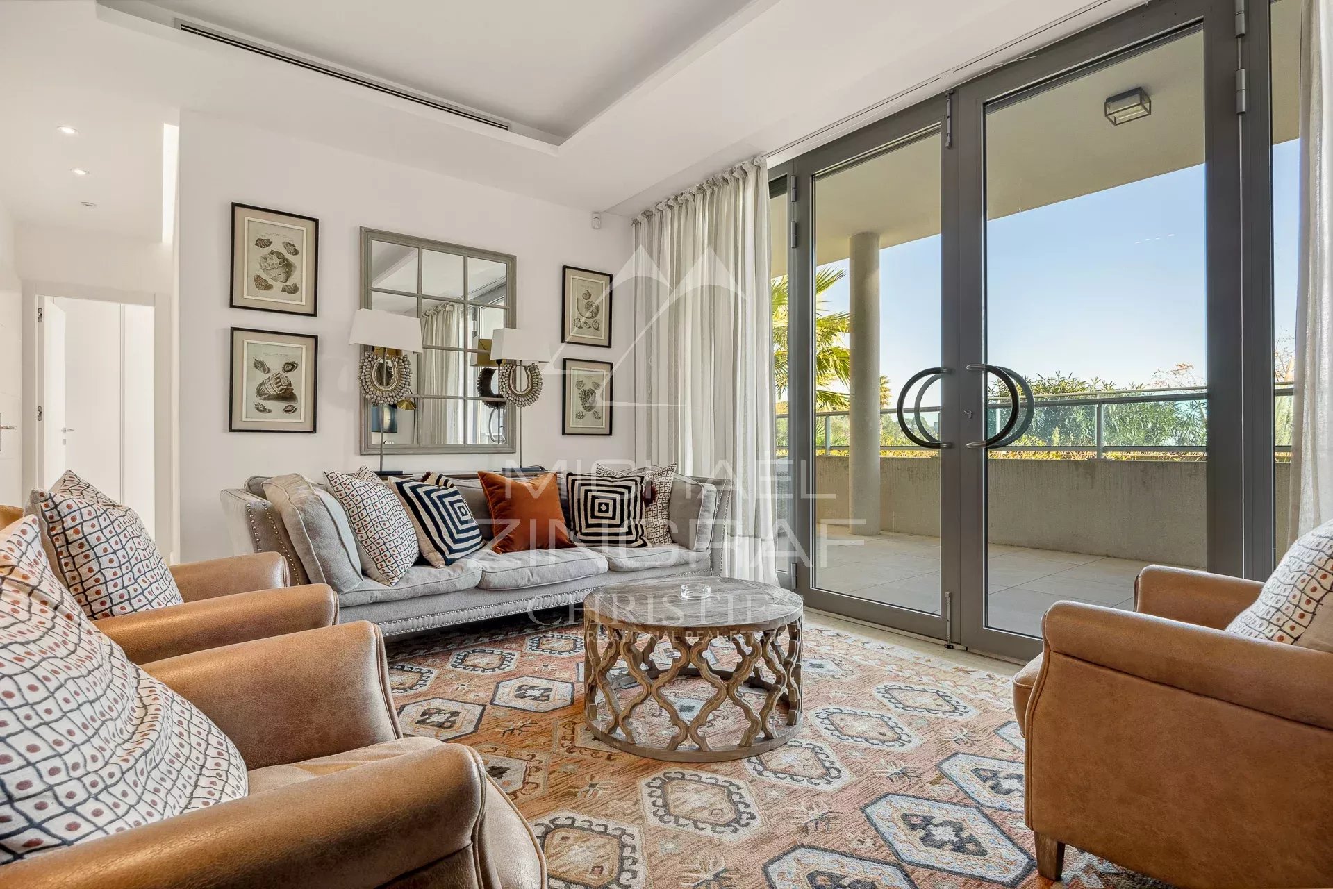 Salon d’appartement au Cap d’Antibes Salon d'un appartement moderne avec canapés et accès à un balcon au Cap d'Antibes.