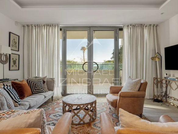 Salon d'un appartement moderne au Cap d'Antibes avec fenêtres et mobilier contemporain.
