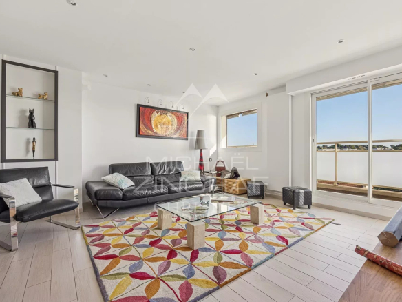 Intérieur d'un appartement moderne avec salon lumineux et vue sur la mer.