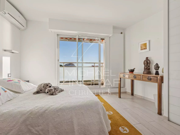 Chambre lumineuse avec lit, accès à un balcon, décor moderne et accueillant.