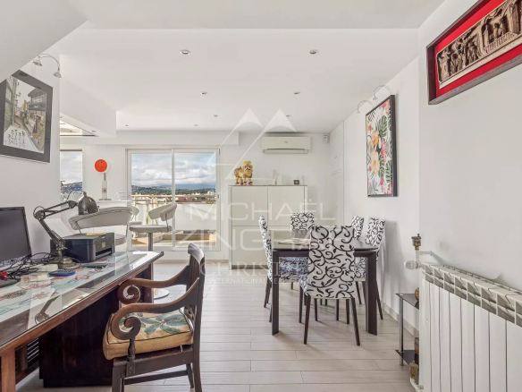 Intérieur d'un appartement moderne avec un bureau, des chaises élégantes et une vue sur la mer.