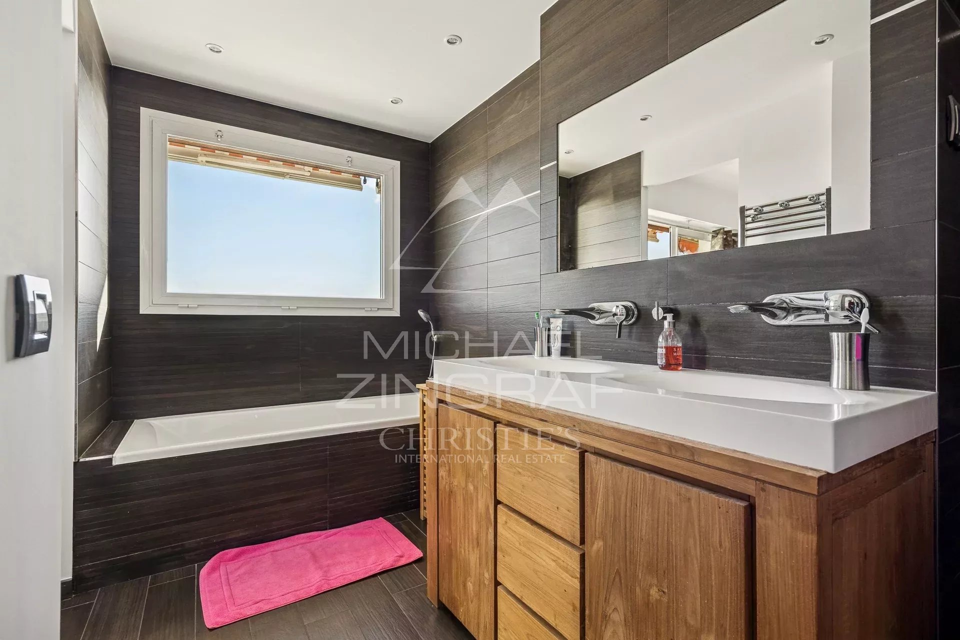 Salle de bain moderne avec baignoire et double vasque, lumière naturelle