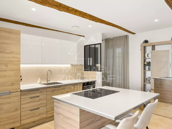 Cuisine moderne d'un duplex à Antibes avec un îlot central et des meubles en bois clair.