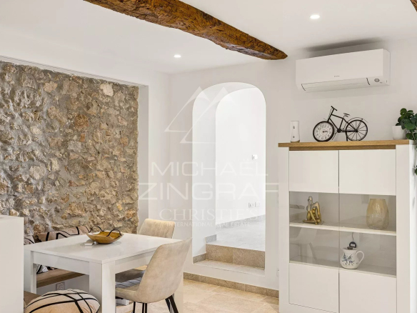 Intérieur d'un duplex à Antibes avec murs en pierre, table à manger et décoration moderne.