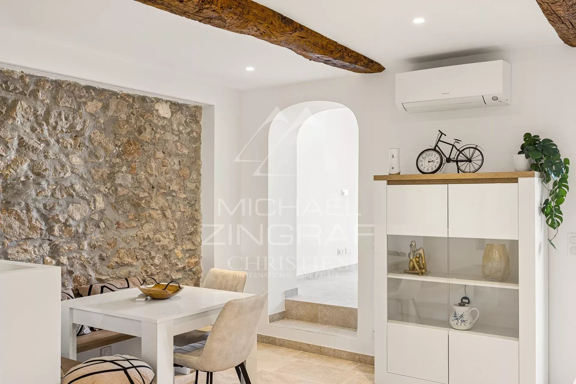 Duplex de charme à Antibes Intérieur d'un duplex à Antibes avec murs en pierre, table à manger et décoration moderne.