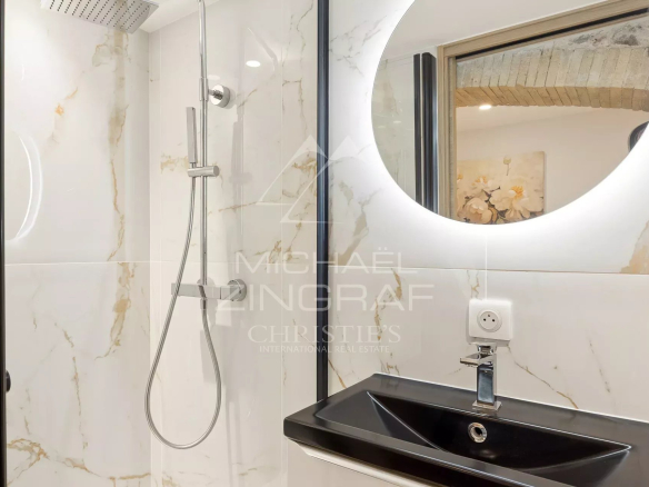 Salle de bain moderne avec douche et lavabo, décorée de marbre blanc et noir.