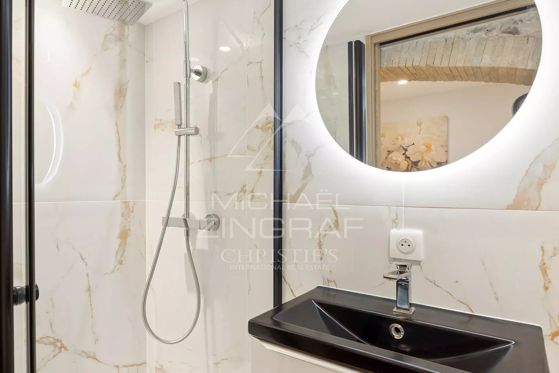 Salle de bain du duplex à Antibes Salle de bain moderne avec douche et lavabo, décorée de marbre blanc et noir.