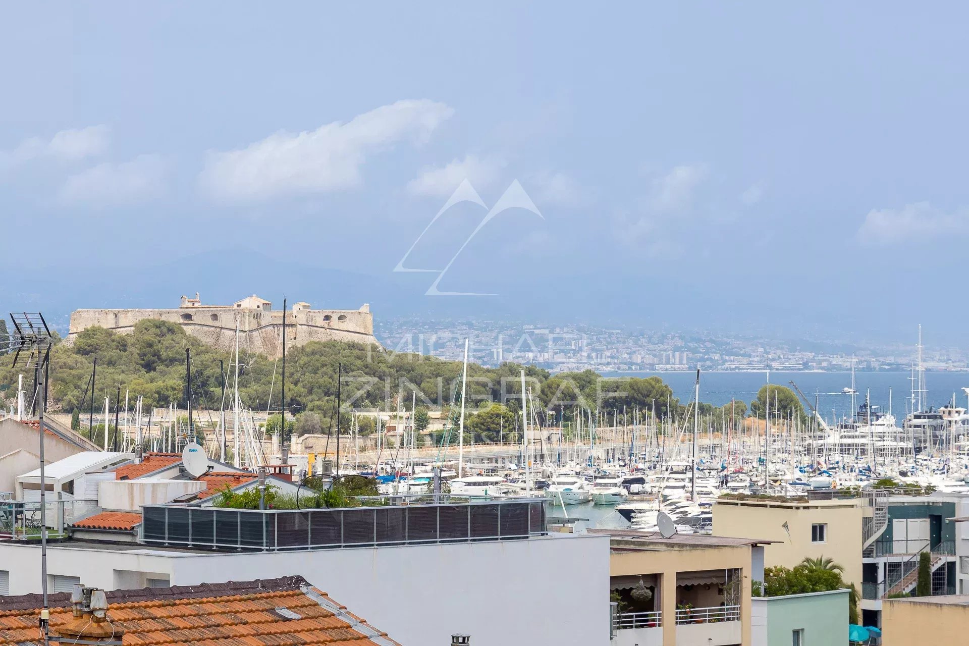 Vue panoramique sur le port et la forteresse à Antibes, avec des bateaux amarrés au port.