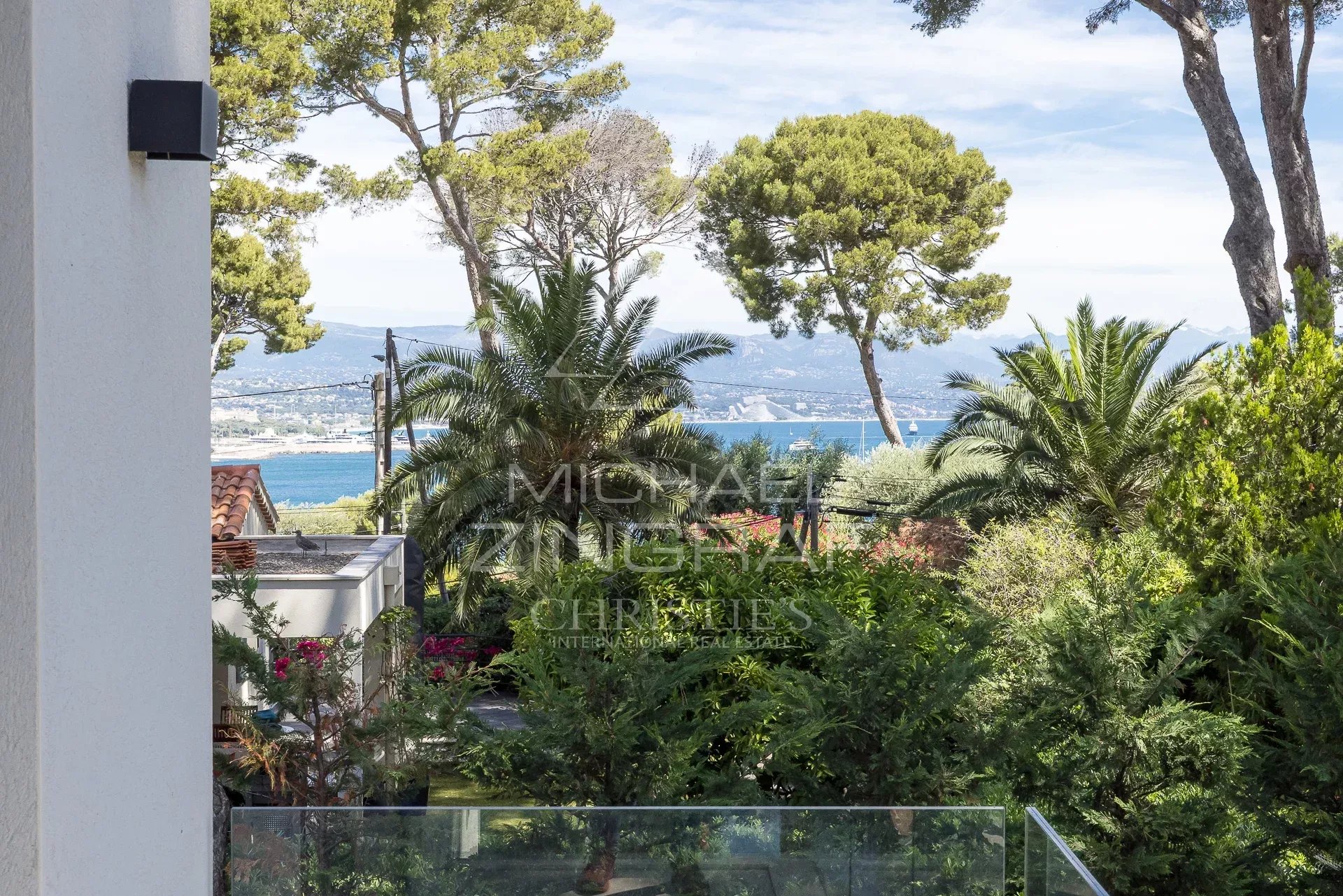 Vue depuis une villa au Cap d’Antibes Vue sur la mer depuis une villa contemporaine avec des arbres et des plantes au Cap d'Antibes.