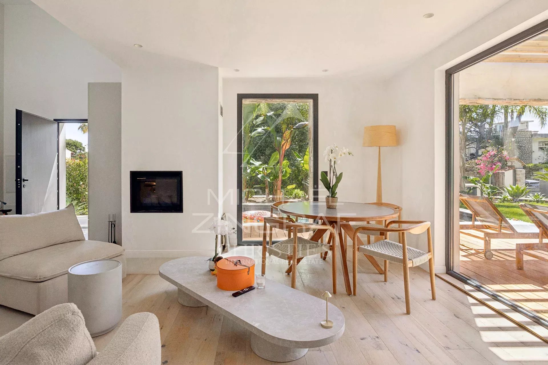 Intérieur d’une villa contemporaine au Cap d’Antibes Intérieur d'une villa contemporaine avec salon lumineux et coin repas, fenêtres ouvertes sur terrasse.