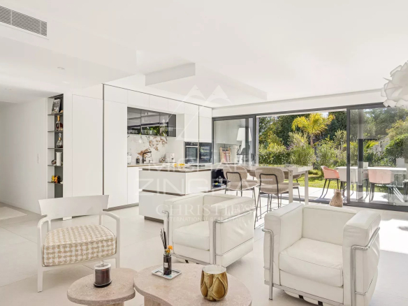 Intérieur d'un appartement moderne avec salon lumineux et cuisine ouverte, donnant sur un jardin.