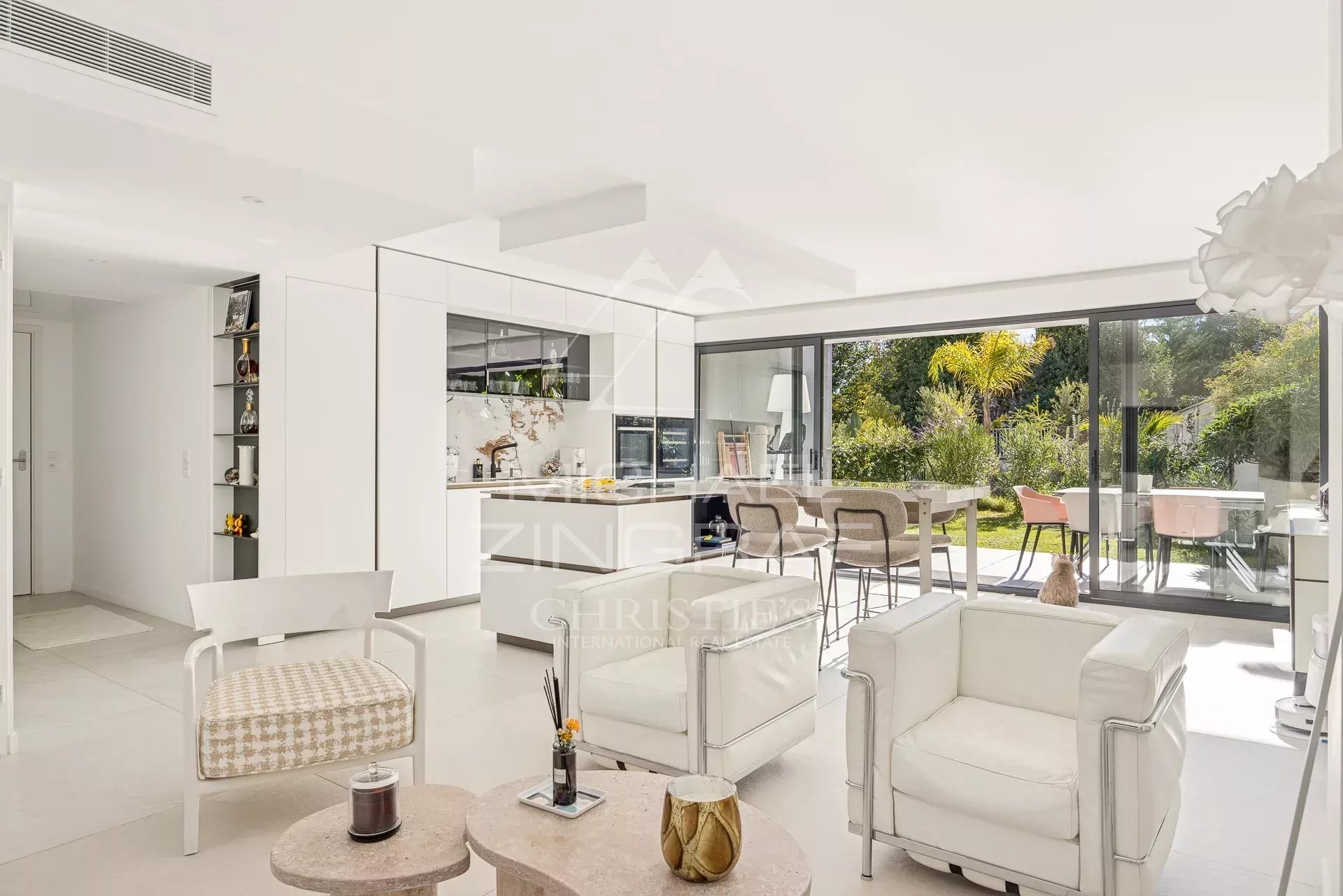 Intérieur d'un appartement moderne avec salon lumineux et cuisine ouverte, donnant sur un jardin.