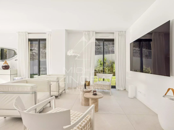 Intérieur d'un appartement moderne avec salon lumineux et accès à un jardin.
