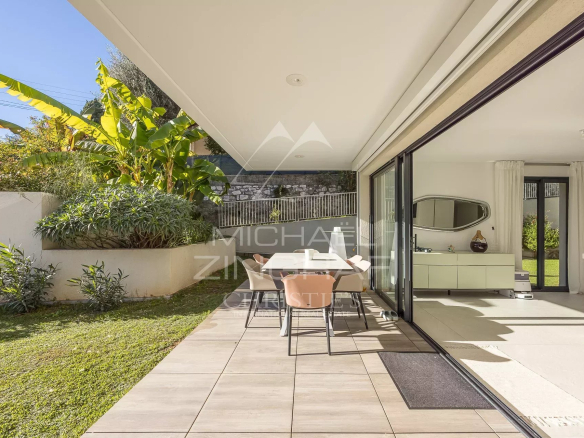 Terrasse d'un appartement en rez-de-jardin avec mobilier et jardin verdoyant à Antibes.