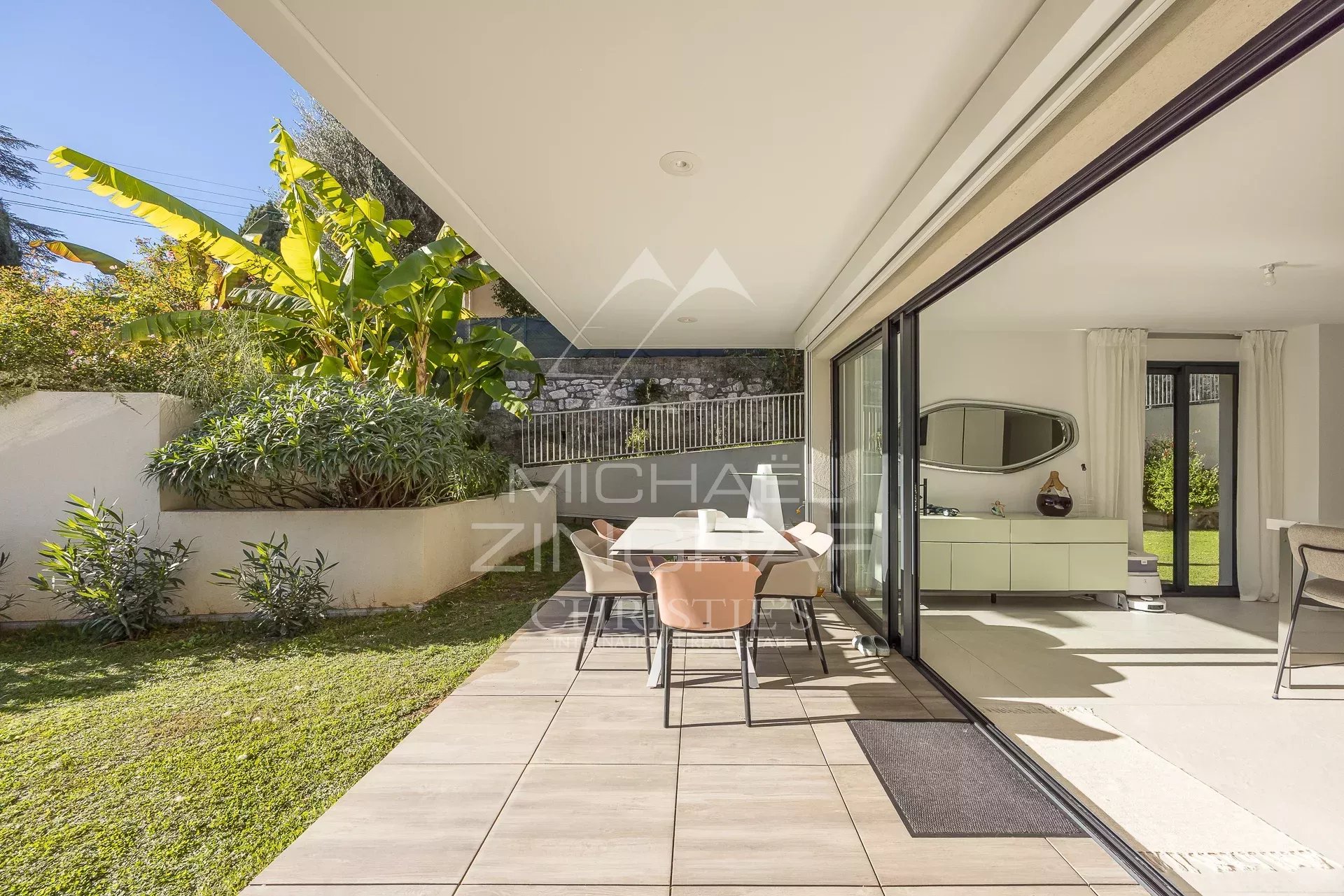 Terrasse d'un appartement en rez-de-jardin avec mobilier et jardin verdoyant à Antibes.
