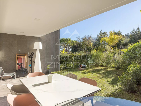 Terrasse d'un appartement en rez-de-jardin avec mobilier moderne et jardin verdoyant à Antibes.