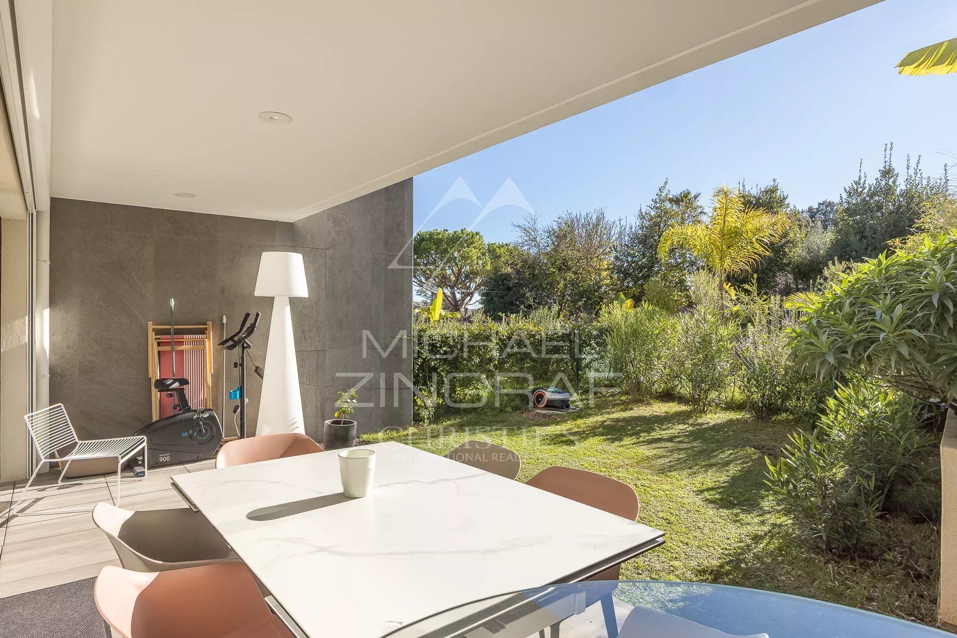 Terrasse d'un appartement en rez-de-jardin avec mobilier moderne et jardin verdoyant à Antibes.