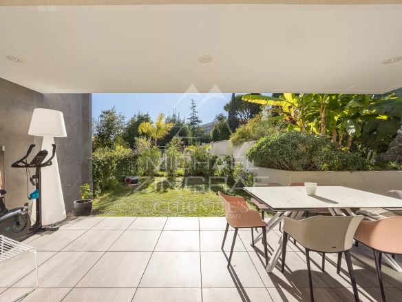 Terrasse d'un appartement en rez-de-jardin avec mobilier moderne et jardin verdoyant à Antibes.
