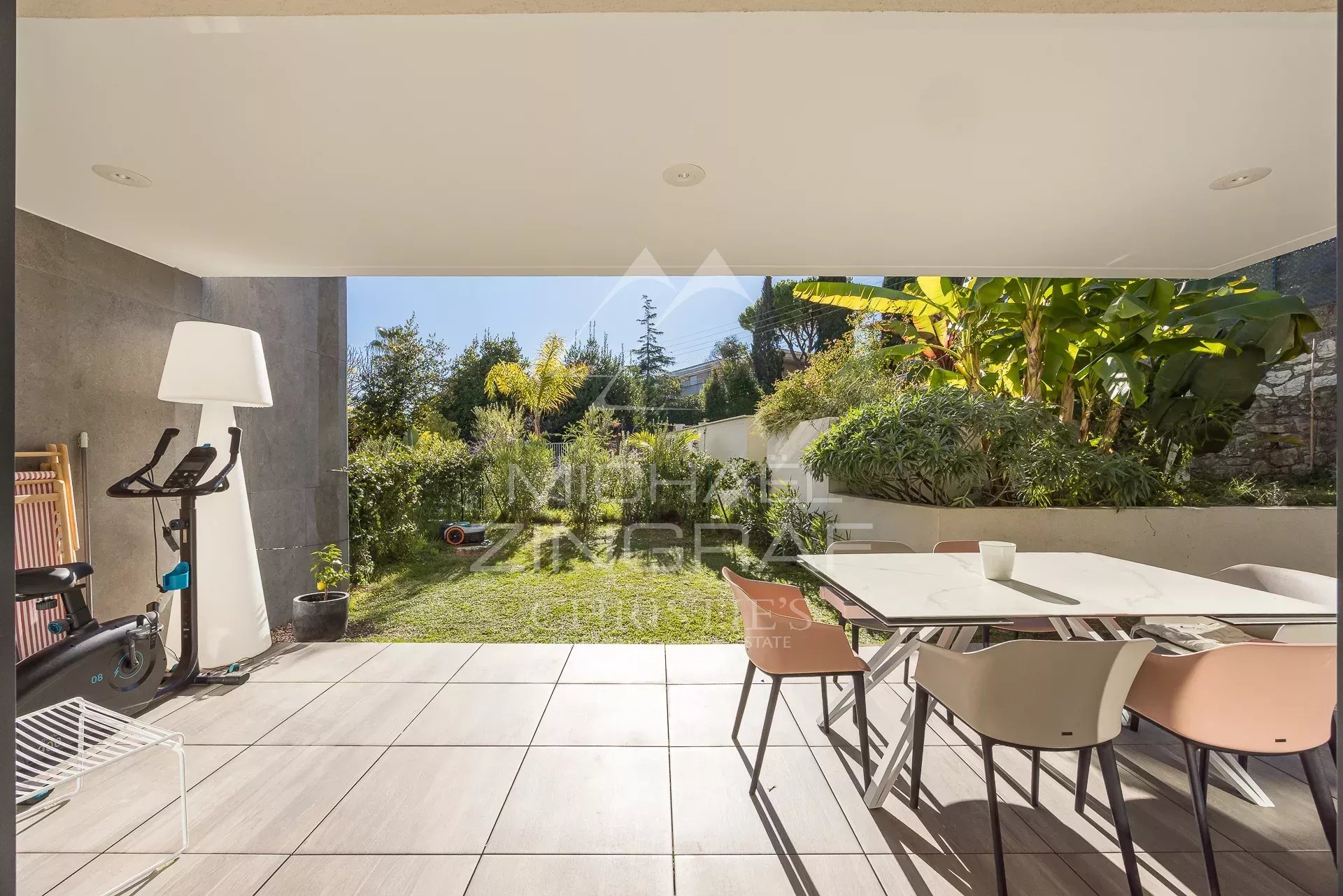 Terrasse d'un appartement en rez-de-jardin avec mobilier moderne et jardin verdoyant à Antibes.