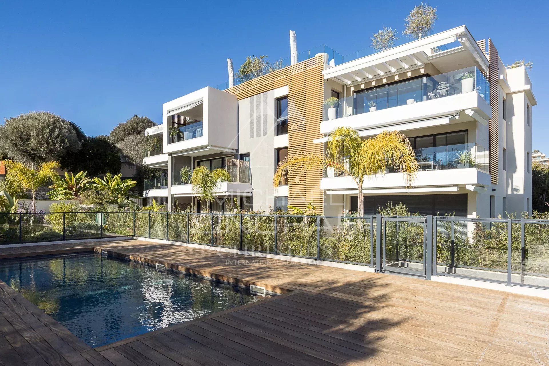 Vue extérieure d'un appartement moderne avec piscine et jardin à Antibes.
