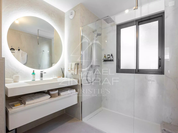 Salle de bain moderne avec douche à l'italienne et lavabo dans un appartement.