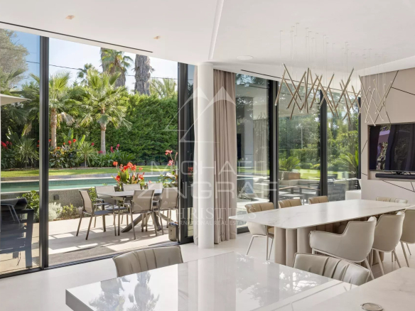 Intérieur d'une villa contemporaine avec salle à manger moderne et vue sur le jardin et la piscine.