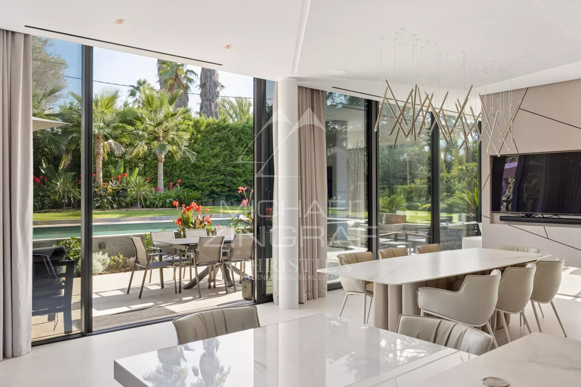 Intérieur d'une villa contemporaine avec salle à manger moderne et vue sur le jardin et la piscine.