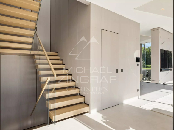 Intérieur d'une villa contemporaine avec un escalier en bois et des murs modernes.