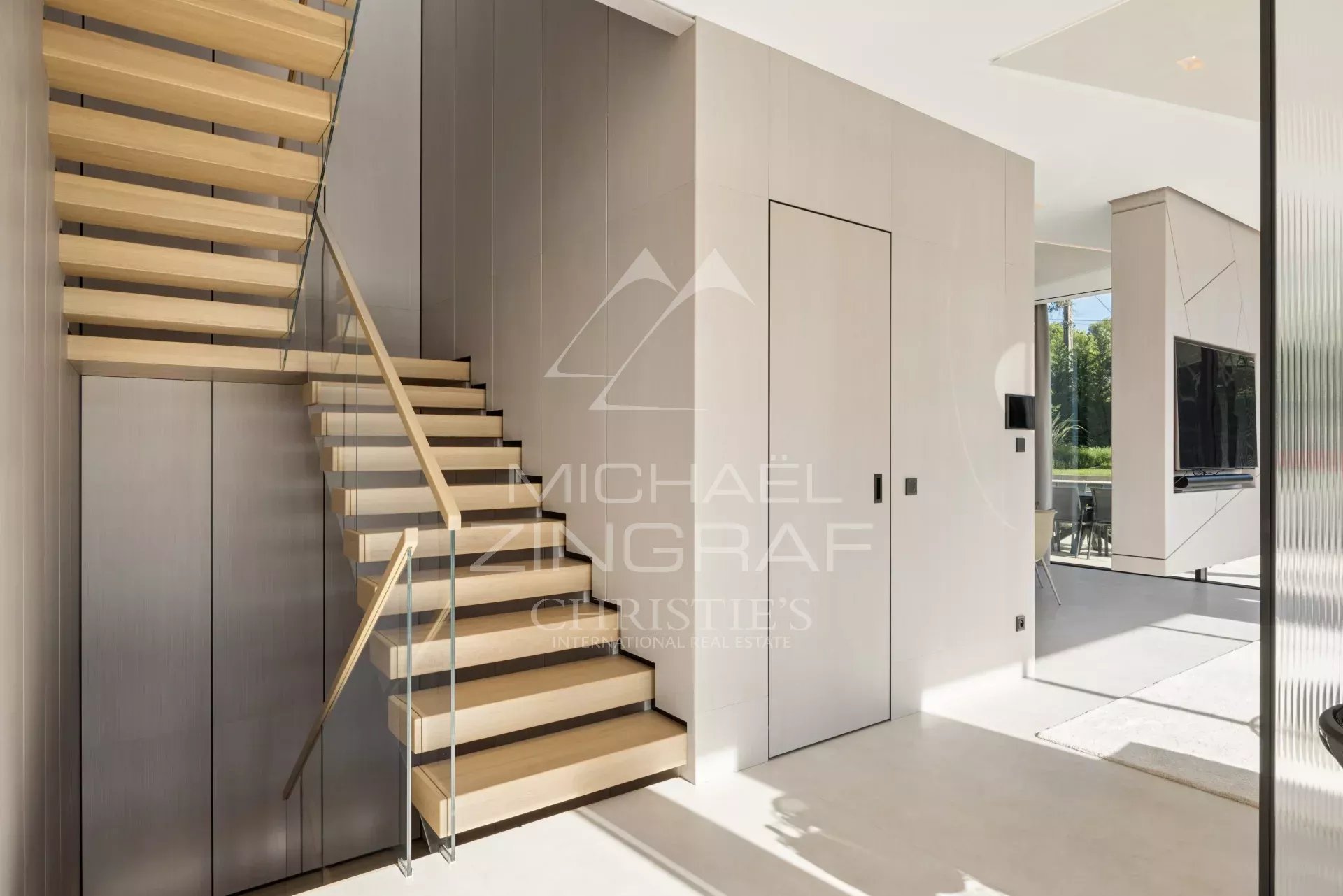 Intérieur d'une villa contemporaine avec un escalier en bois et des murs modernes.