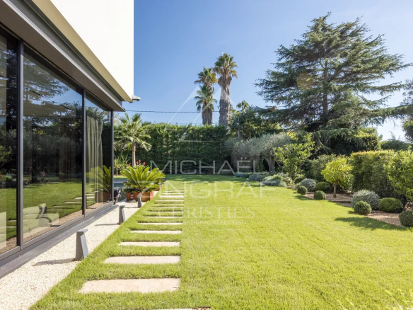 Jardin paysager d'une villa contemporaine avec pelouse et palmiers à Antibes.