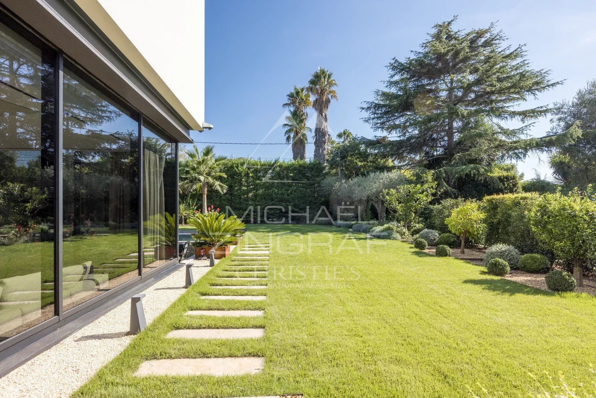 Jardin paysager d'une villa contemporaine avec pelouse et palmiers à Antibes.