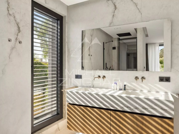 Salle de bain moderne avec lavabo en marbre et fenêtres à lattes.