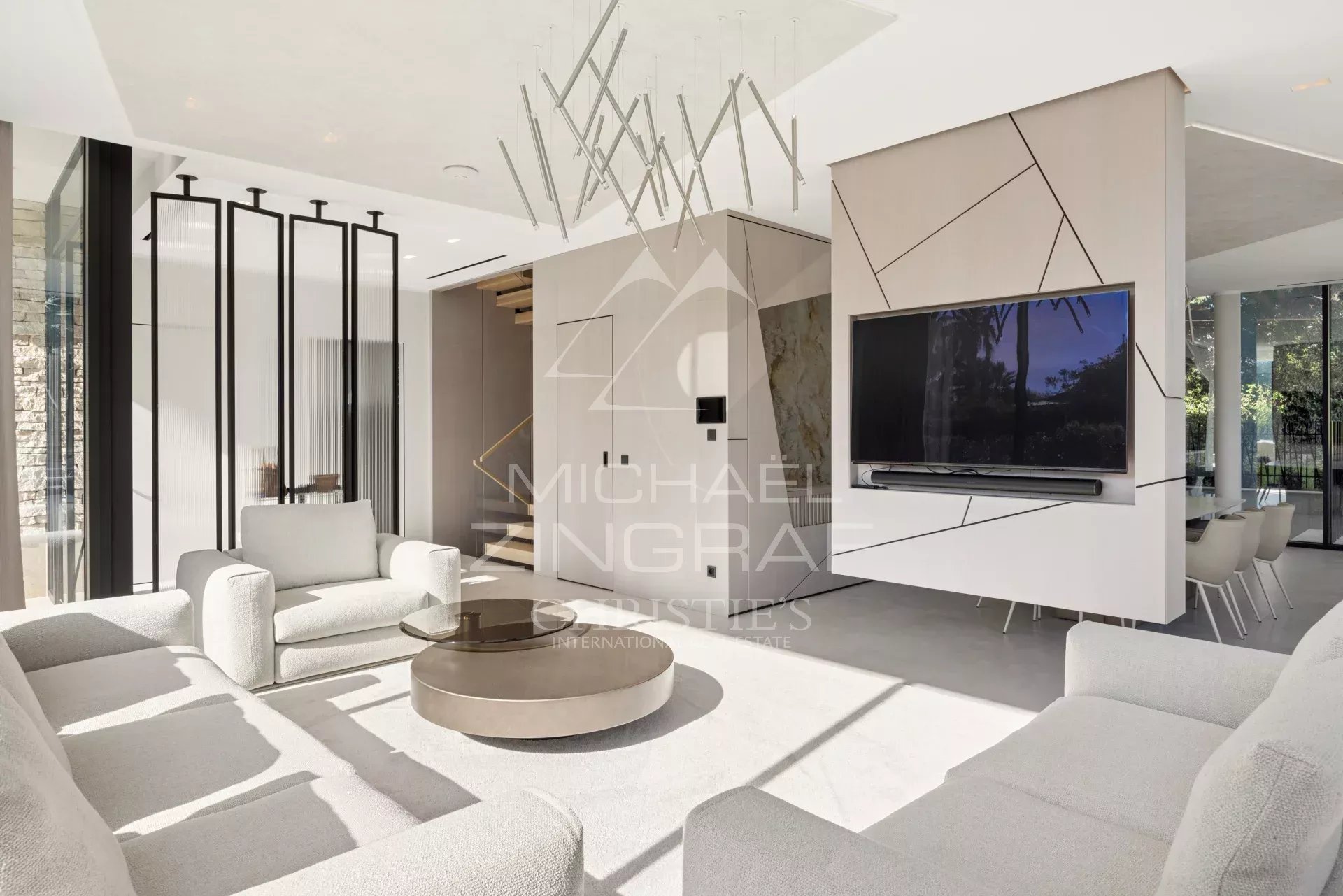 Intérieur d'une villa contemporaine à Cap d'Antibes avec salon moderne et télévision murale.