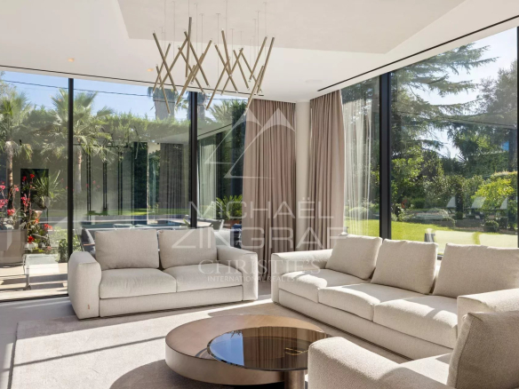 Intérieur d'une villa contemporaine à Cap d'Antibes, salon lumineux avec grandes baies vitrées et mobilier moderne.
